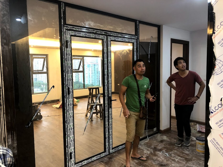 Cửa nhôm kính trượt lắp đặt trong căn hộ đang hoàn thiện, thợ thi công đứng kiểm tra chất lượng